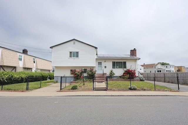 40 Atwood St, Revere, MA 02151 - view of front of house featuring a gate, solar panels, a fenced front yard, and a chimney