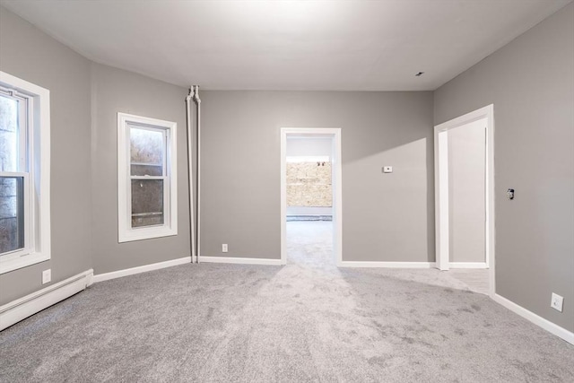 carpeted spare room featuring baseboards, a healthy amount of sunlight, and baseboard heating