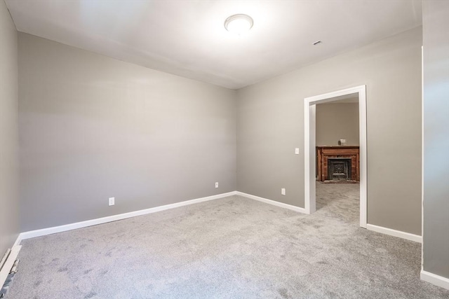 carpeted empty room with a fireplace and baseboards