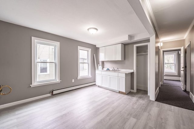 kitchen with light wood-style flooring, white cabinetry, baseboards, a baseboard heating unit, and light countertops