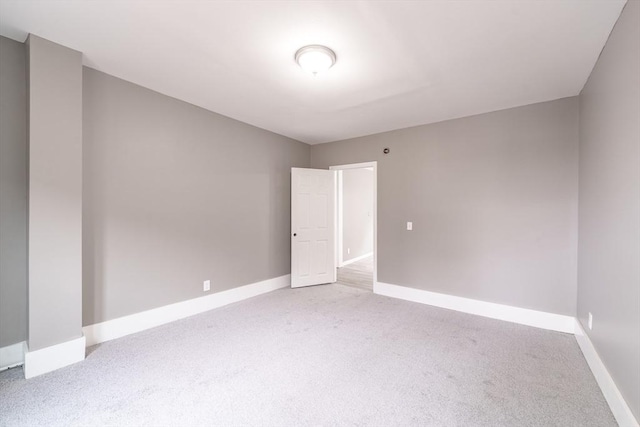 spare room with baseboards and carpet floors
