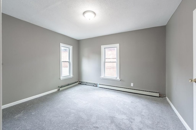 carpeted empty room featuring a textured ceiling, baseboards, and a baseboard heating unit