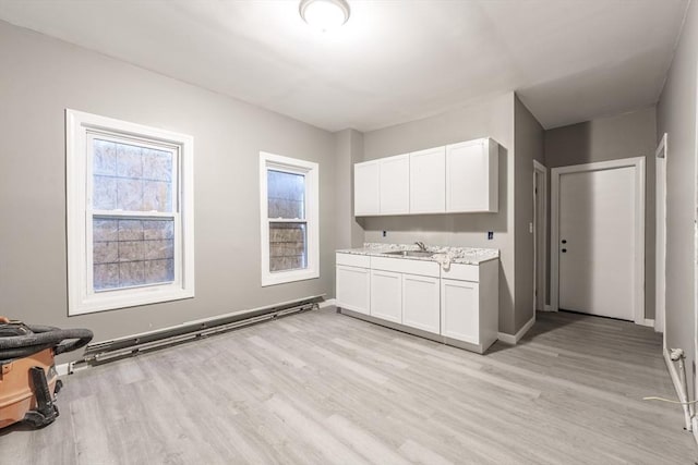 interior space with baseboards, light wood-type flooring, and a sink
