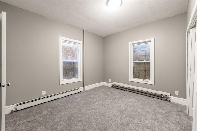 carpeted spare room featuring a baseboard heating unit, a wealth of natural light, and a textured ceiling