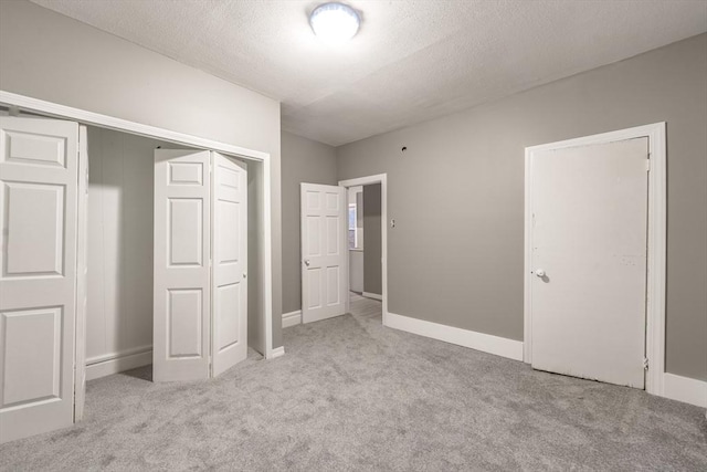 unfurnished bedroom with a textured ceiling, carpet floors, a closet, and baseboards