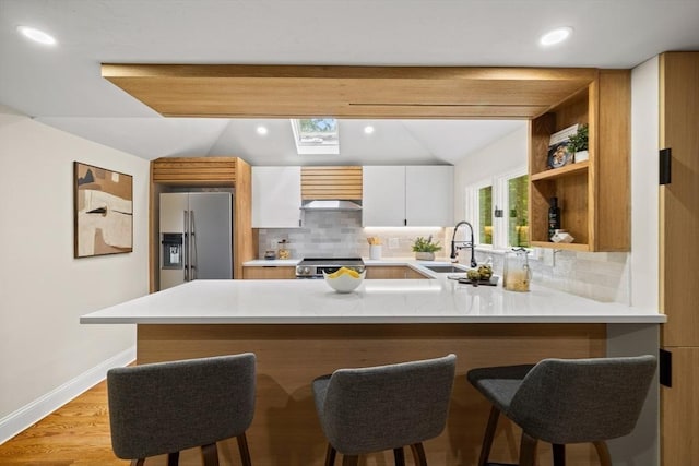616 Grove St, Framingham, MA 01701 - kitchen featuring high end fridge, backsplash, a peninsula, a skylight, and recessed lighting