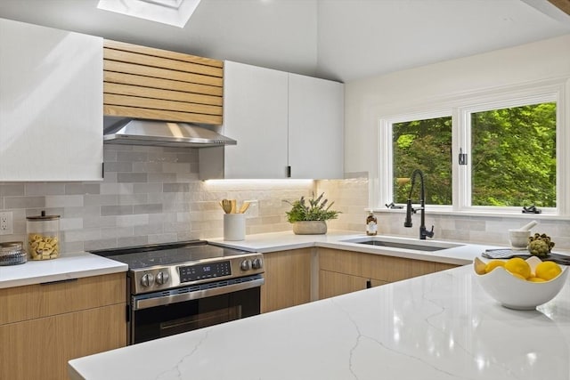 616 Grove St, Framingham, MA 01701 - kitchen with stainless steel electric stove, extractor fan, light stone countertops, a skylight, and backsplash