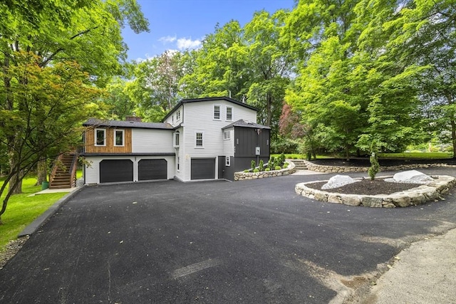 616 Grove St, Framingham, MA 01701 - view of side of property featuring a garage, stairway, asphalt driveway, and view of wooded area