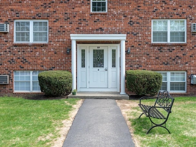 property entrance with brick siding and a lawn
