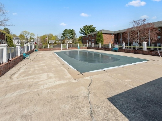 community pool featuring fence, a residential view, and a patio area