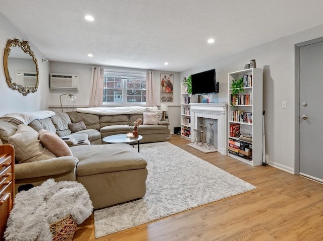 living room with a wall unit AC, light wood-type flooring, a brick fireplace, recessed lighting, and baseboards