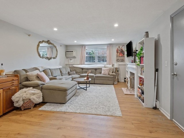 living room featuring a wall unit AC, light wood finished floors, and recessed lighting