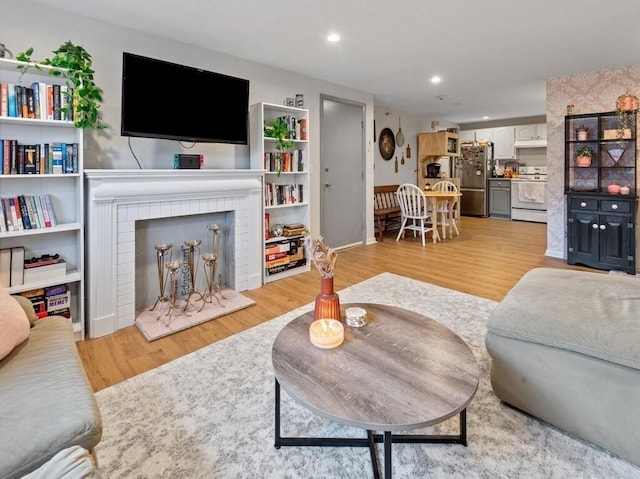 living room with light wood finished floors, recessed lighting, a fireplace, and baseboards