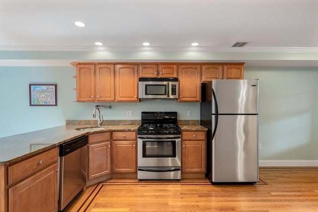 kitchen featuring light stone counters, a peninsula, stainless steel appliances, open shelves, and a sink