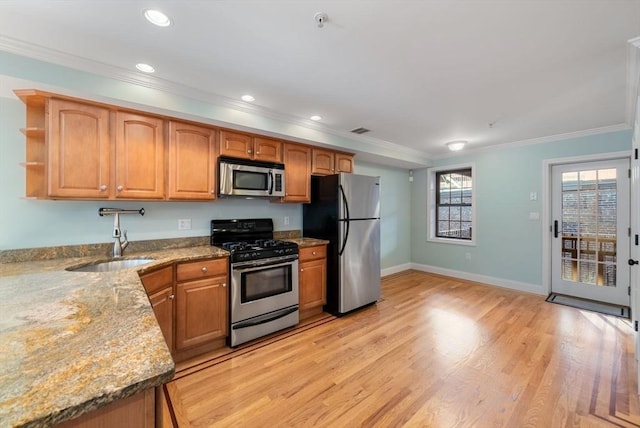 kitchen featuring light stone counters, stainless steel appliances, a sink, open shelves, and crown molding