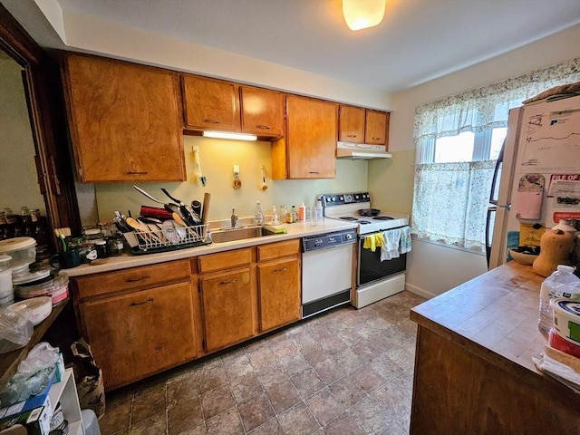 12 Chadwick Ct Unit 12, Amherst, MA 01002 - kitchen featuring white appliances, under cabinet range hood, brown cabinetry, a sink, and stone finish flooring