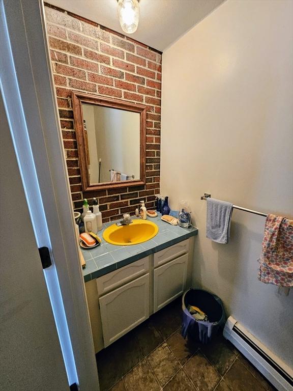 12 Chadwick Ct Unit 12, Amherst, MA 01002 - bathroom with baseboard heating, vanity, and decorative backsplash