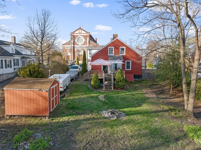 back of property featuring stairway, a chimney, a yard, an outbuilding, and a deck
