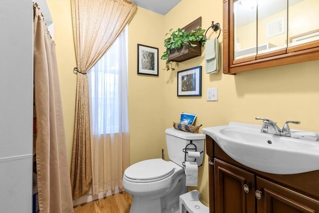 full bathroom featuring toilet, vanity, wood finished floors, and visible vents