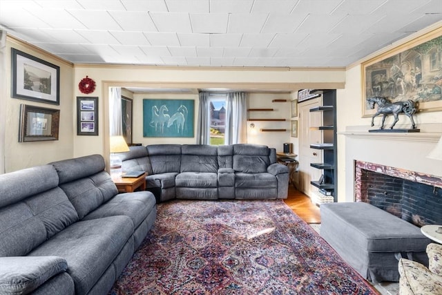 living room with a fireplace, wood finished floors, and crown molding