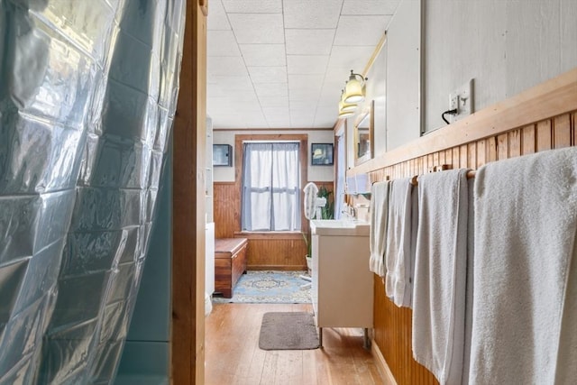 bathroom with wainscoting, wood walls, a shower, vanity, and wood-type flooring