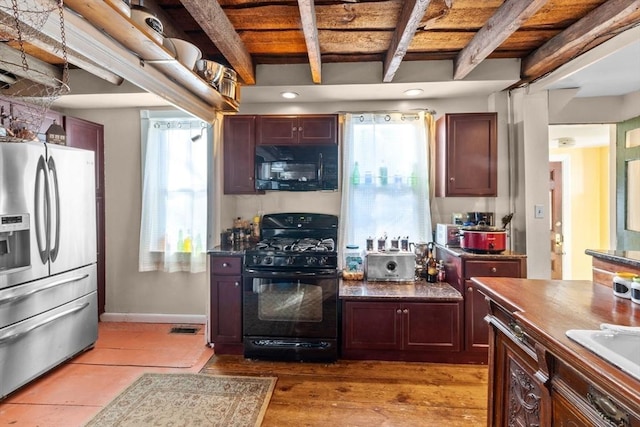 kitchen with dark countertops, baseboards, visible vents, beamed ceiling, and black appliances