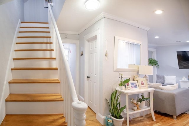 stairway with hardwood / wood-style flooring and crown molding