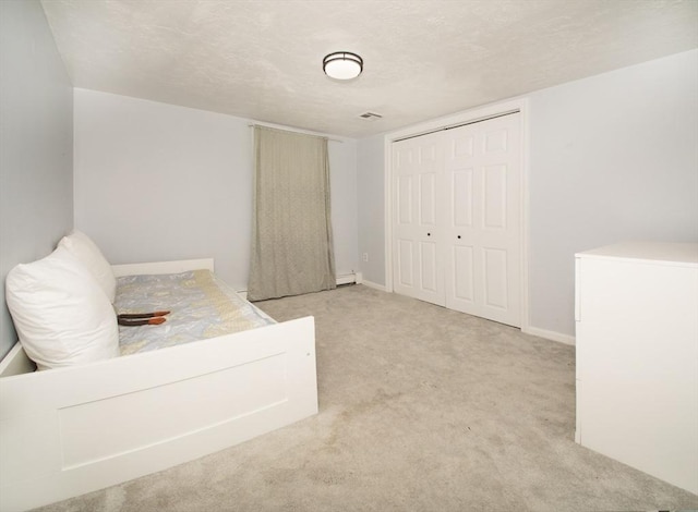 bedroom with a textured ceiling, light carpet, and a closet