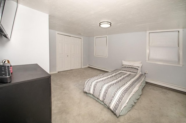 bedroom with carpet flooring, a closet, a textured ceiling, and a baseboard radiator