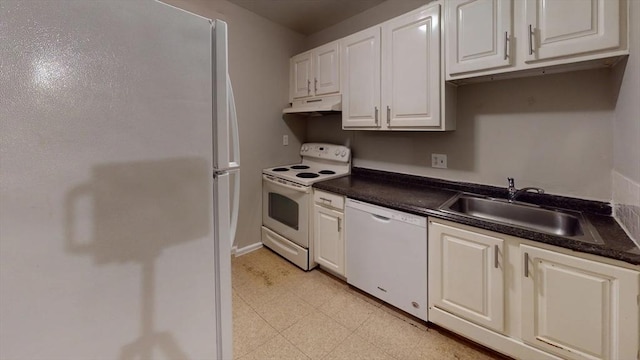 kitchen featuring dark countertops, white cabinetry, a sink, white appliances, and under cabinet range hood