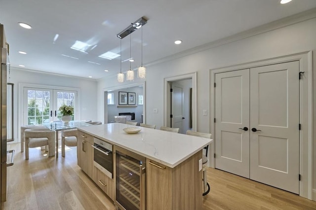 kitchen with wine cooler, french doors, light wood finished floors, hanging light fixtures, and a kitchen island