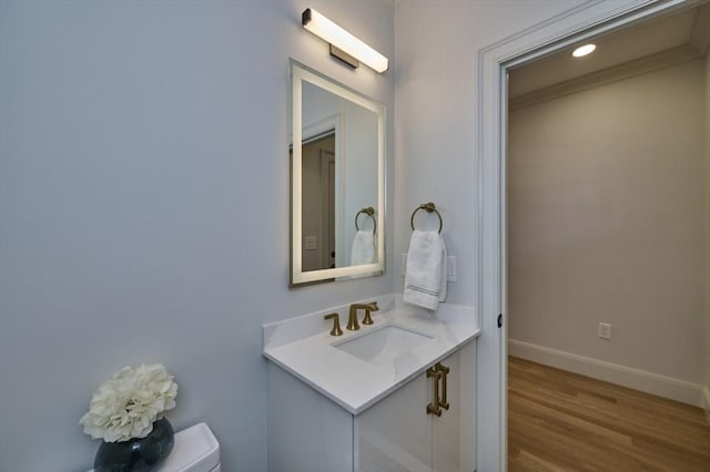 bathroom featuring toilet, wood finished floors, vanity, and baseboards