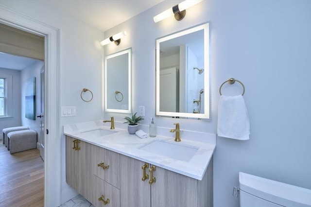 bathroom with double vanity, wood finished floors, a sink, and toilet