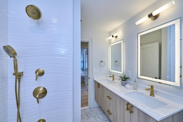 bathroom with a tile shower, double vanity, tile patterned flooring, and a sink