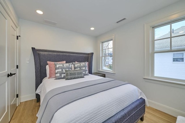 bedroom featuring light wood-type flooring, visible vents, and baseboards