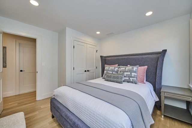 bedroom with recessed lighting, wood finished floors, visible vents, baseboards, and a closet