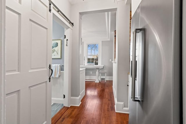 hallway with dark wood-style flooring, baseboards, and a barn door