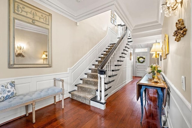 staircase with wood-type flooring, ornamental molding, wainscoting, and a decorative wall