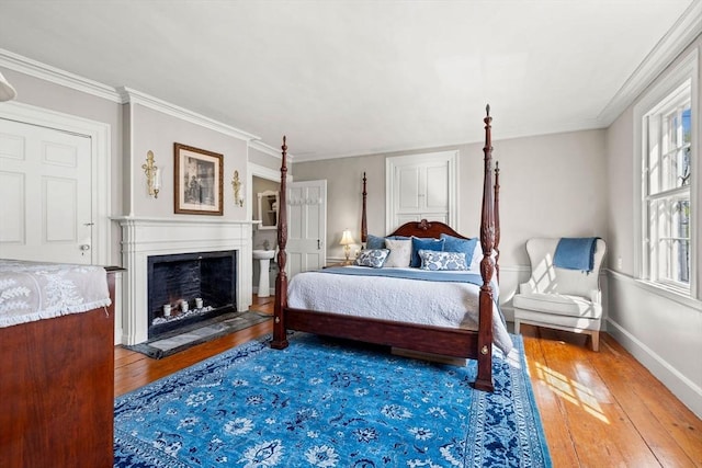 bedroom with a fireplace, baseboards, ornamental molding, and wood-type flooring