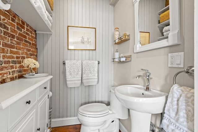 half bathroom with wood walls, brick wall, and toilet