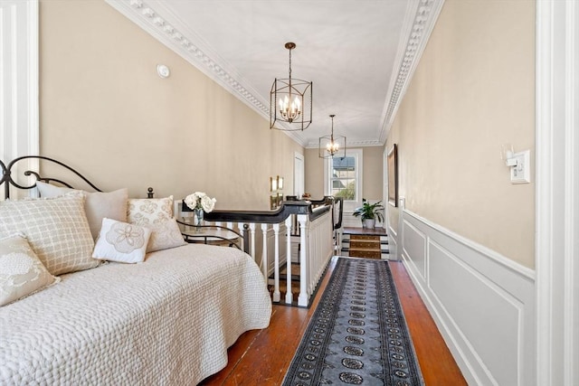 bedroom featuring crown molding, a wainscoted wall, an inviting chandelier, and wood finished floors
