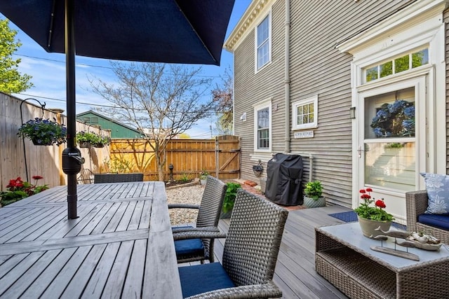 wooden deck with outdoor dining area, a fenced backyard, and area for grilling