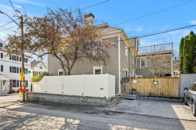 view of side of home featuring a fenced front yard and a chimney