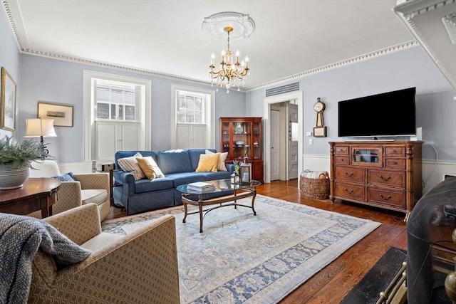 living room with a wainscoted wall, dark wood-type flooring, and a notable chandelier