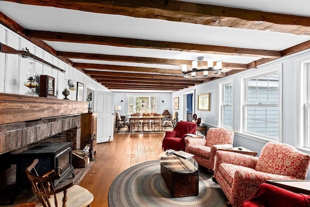 living area featuring plenty of natural light, beamed ceiling, an inviting chandelier, and hardwood / wood-style floors