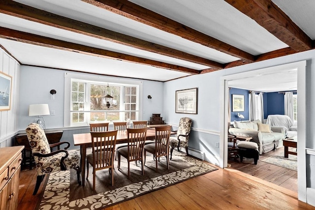 dining space featuring hardwood / wood-style floors, beamed ceiling, and a baseboard heating unit