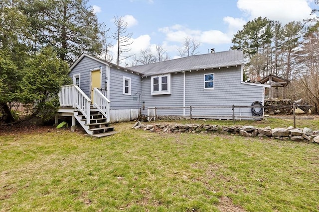 back of property with a shingled roof and a lawn