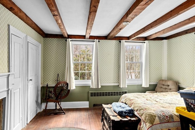 bedroom with radiator heating unit, wallpapered walls, baseboards, and wood-type flooring