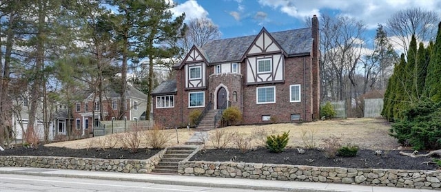 tudor home with brick siding and a chimney