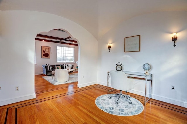 office area featuring arched walkways, lofted ceiling with beams, baseboards, and wood-type flooring